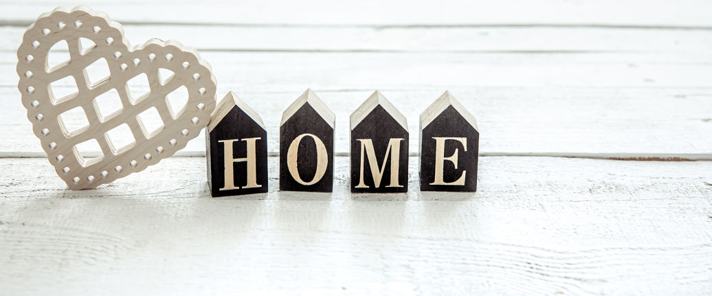 Bloques decorativos en forma de casitas negras con letras que forman la palabra HOME sobre fondo blanco
